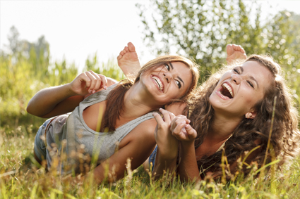 Girls in meadow smile after receiving dental work from an Allex TX cosmetic dentist.