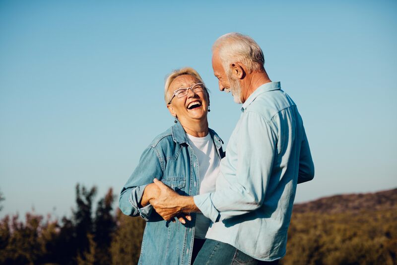 Two elderly people smiling after enjoying restorative dentistry.
