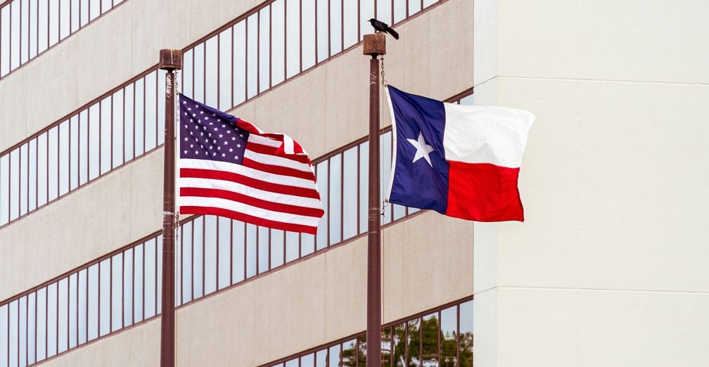 Texas and American flags flying outside an office building in Plano, TX