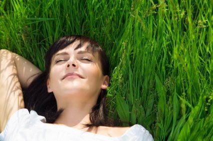 A young woman reclining in grass after a relaxing dental visit in Plano.