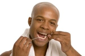 A man flossing to prevent gum disease complications in Plano.